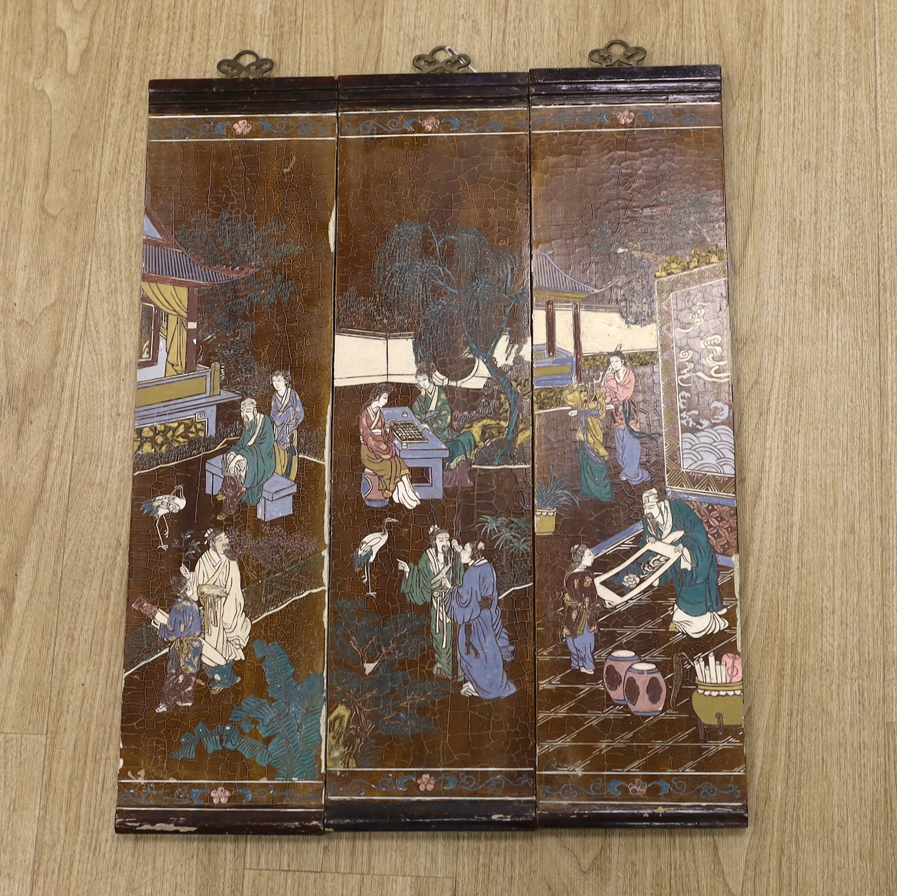 Three Chinese wood lacquered panels of domestic scenes, each 69 x 18cm